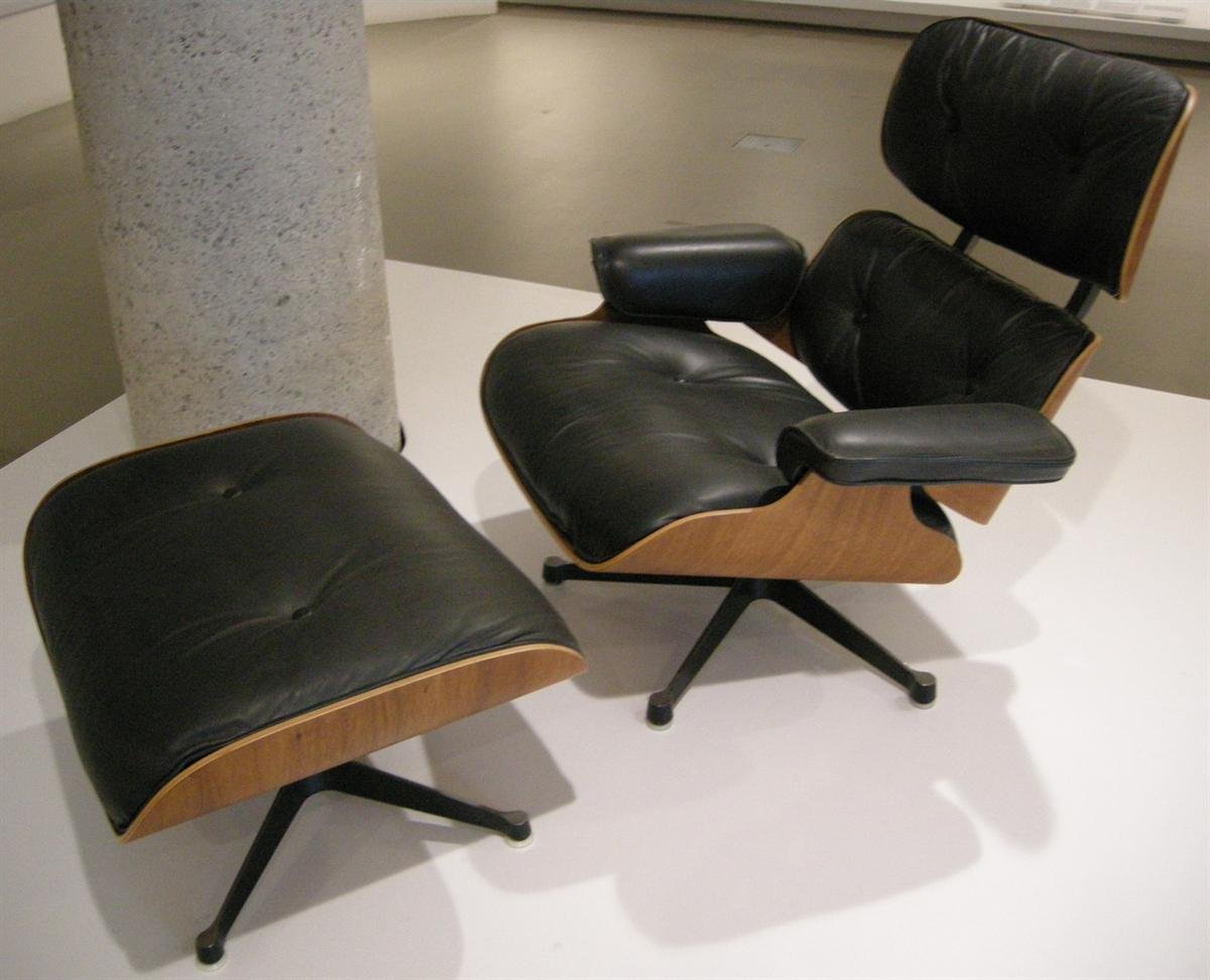 An Eames Lounge Chair 670 and ottoman in black leather and moulded walnut plywood