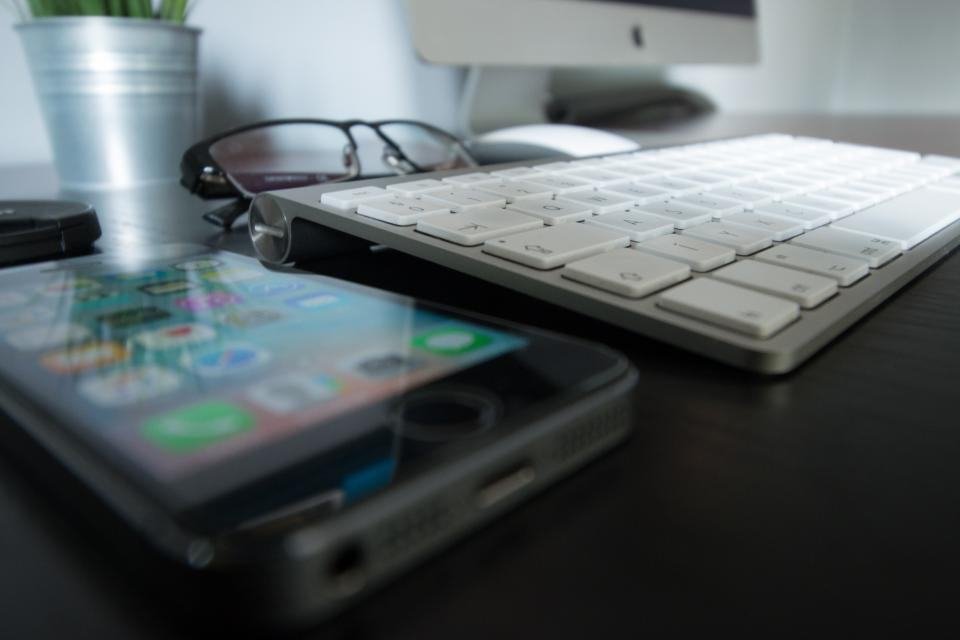 Glasses resting beside a keyboard and screen on a desk