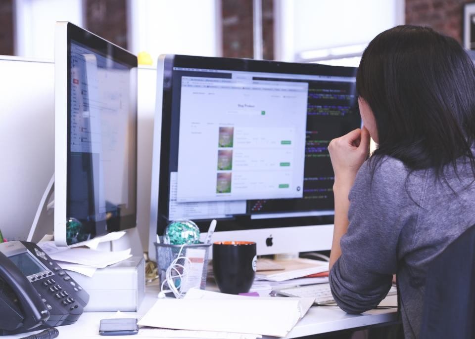 A person working at a dual-monitor desk setup